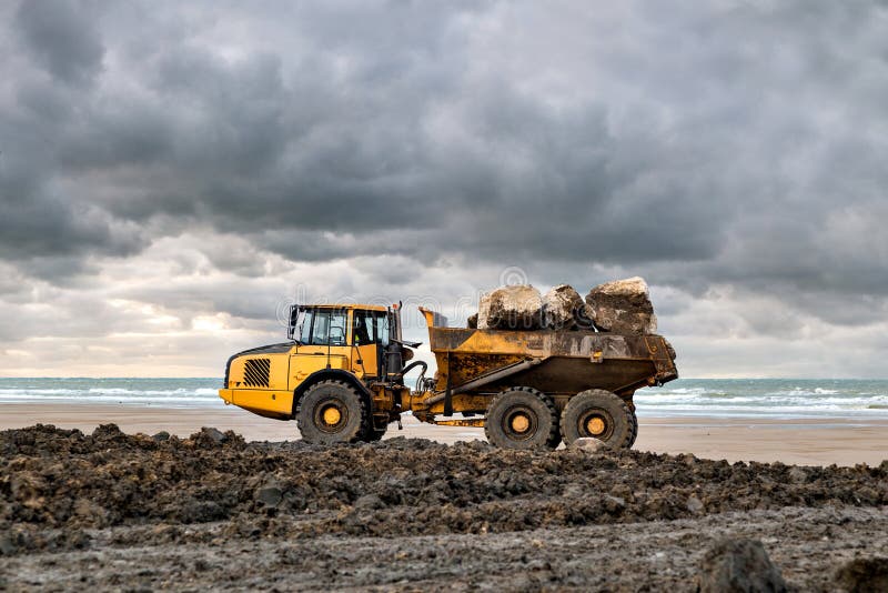 dumper at work on a construction site near a beach. dumper at work on a construction site near a beach