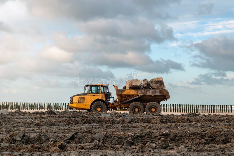 dumper at work on a construction site near a beach. dumper at work on a construction site near a beach