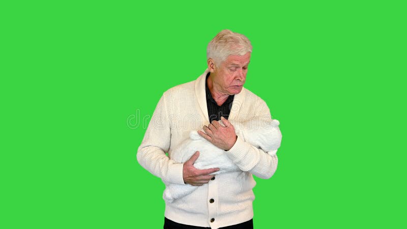 śpiący i zmęczony dziadek trzymający dziecko na zielonym ekranie chroma key.
