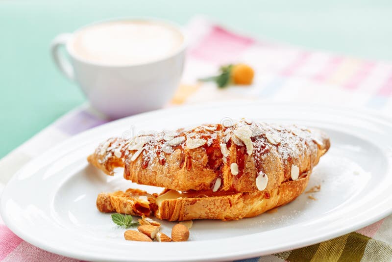 Świezi croissants zakrywający z dżemem i pokrojonym migdałem na zamazanym coffe filiżanki tle dla śniadania zdjęcie royalty free Świezi croissants zakrywający z dżemem i pokrojonym migdałem na zamazanym coffe filiżanki tle dla śniadania zdjęcie royalty free