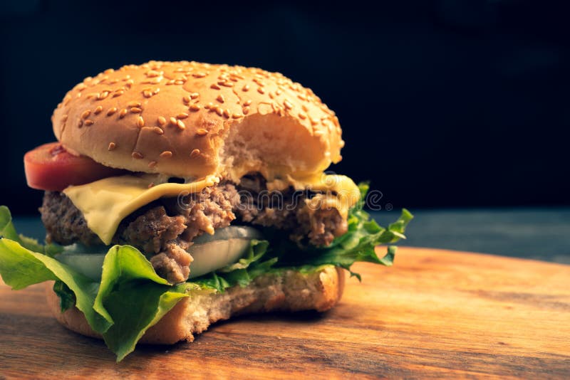 Świezi domowej roboty hamburgery, wyśmienicie świezi warzywa, sałata, pomidory które gryźć na tnącej desce, ser bezpłatna przestr obraz royalty free Świezi domowej roboty hamburgery, wyśmienicie świezi warzywa, sałata, pomidory które gryźć na tnącej desce, ser bezpłatna przestr obraz royalty free