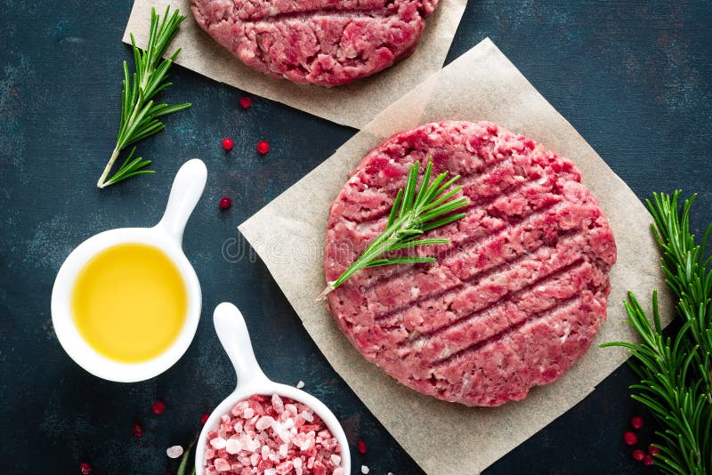 Świezi minced wołowina mięśni hamburgery z pikantność na ciemnym tle Surowy zmielony wołowiny mięso fotografia stock Świezi minced wołowina mięśni hamburgery z pikantność na ciemnym tle Surowy zmielony wołowiny mięso fotografia stock