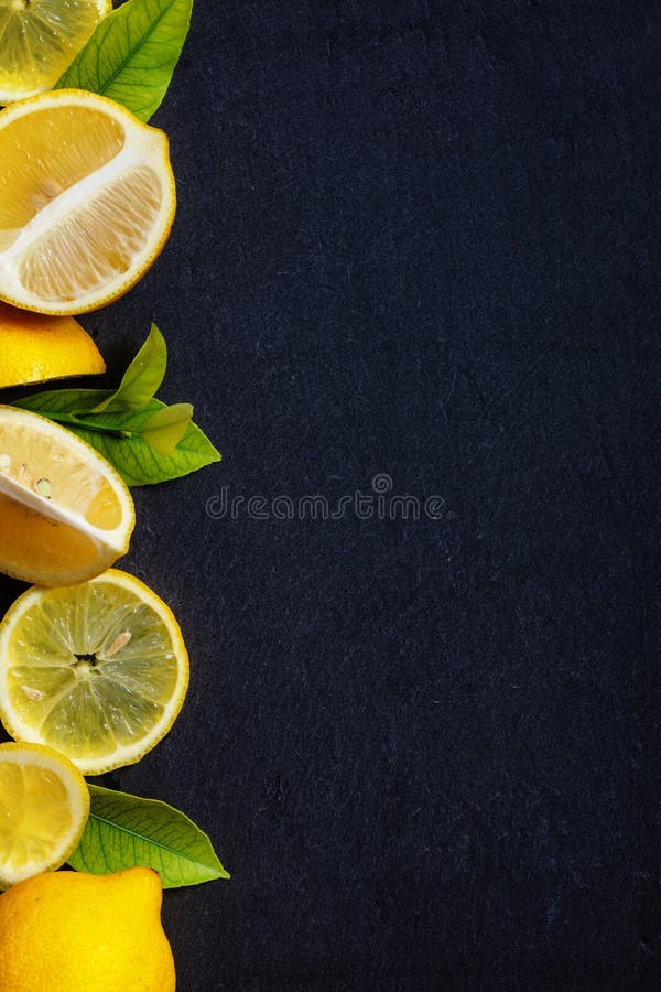 Świeże rżnięte i całe cytryny z zielonymi liśćmi na zmroku kamienia stole obrazy royalty free Świeże rżnięte i całe cytryny z zielonymi liśćmi na zmroku kamienia stole obrazy royalty free