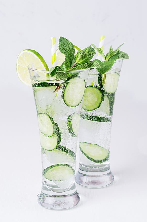 Świeży detox koktajl ogórek, wapno, mennica, słoma z bąblami, krople na miękkim białym drewnianym tle fotografia stock Świeży detox koktajl ogórek, wapno, mennica, słoma z bąblami, krople na miękkim białym drewnianym tle fotografia stock