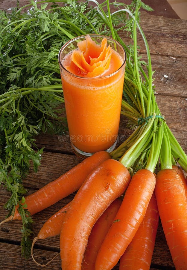 Świeży marchwianego soku szkło z świeżymi organicznie marchewkami