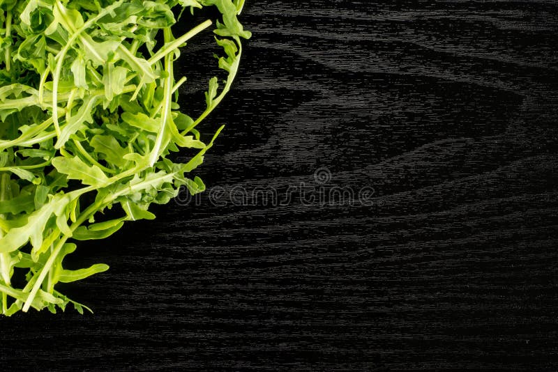 Świeży Surowy Arugula Rucola na czarnym drewnie obraz royalty free Świeży Surowy Arugula Rucola na czarnym drewnie obraz royalty free