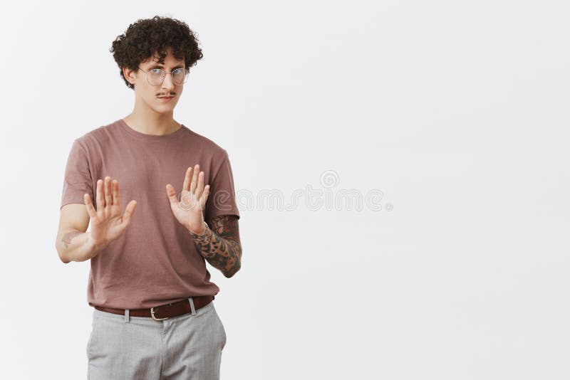 No I refuse. Portrait of good-looking displeased and intense guy with curly dark hair tattooed arm and moustache pulling palms in restrain and stop gesture frowning rejecting bad advice or offer. No I refuse. Portrait of good-looking displeased and intense guy with curly dark hair tattooed arm and moustache pulling palms in restrain and stop gesture frowning rejecting bad advice or offer.