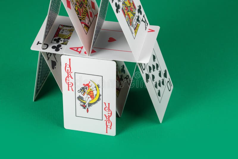 żartowniś na tle domu kart na zielonym stole gry zdjęcia stock
