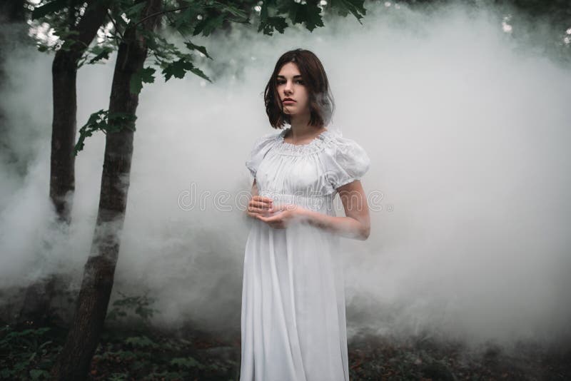 Żeńska ofiara w biel sukni w mglistym lesie obrazy stock Żeńska ofiara w biel sukni w mglistym lesie obrazy stock
