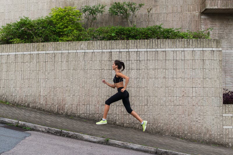 Żeński biegacza biegać ciężki na grodzkiej ulicie Sporty młoda kobieta robi cardio ćwiczeniom outdoors obraz stock Żeński biegacza biegać ciężki na grodzkiej ulicie Sporty młoda kobieta robi cardio ćwiczeniom outdoors obraz stock