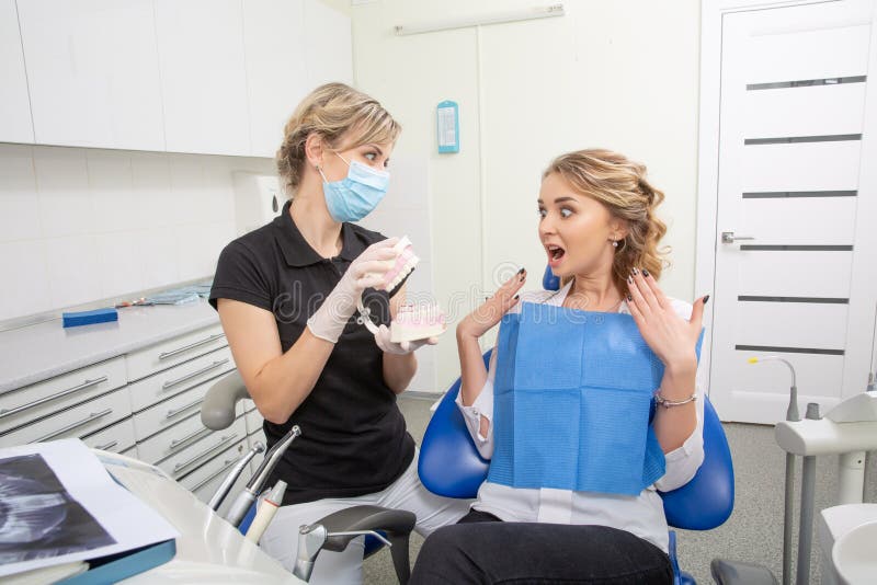 Żeński dentysta opowiada pacjent, pokazuje stomatologicznego szczęka modela w stomatologicznym kliniki biurze Stomatology i opiek zdjęcie stock Żeński dentysta opowiada pacjent, pokazuje stomatologicznego szczęka modela w stomatologicznym kliniki biurze Stomatology i opiek zdjęcie stock