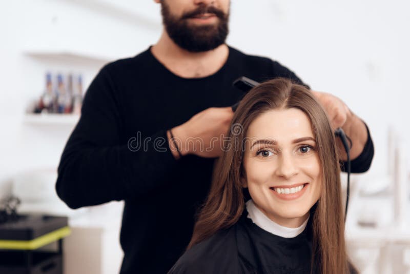 Żeński fryzjer prostuje brown włosy ładna kobieta używa włosy żelazo w piękno salonie obrazy royalty free Żeński fryzjer prostuje brown włosy ładna kobieta używa włosy żelazo w piękno salonie obrazy royalty free