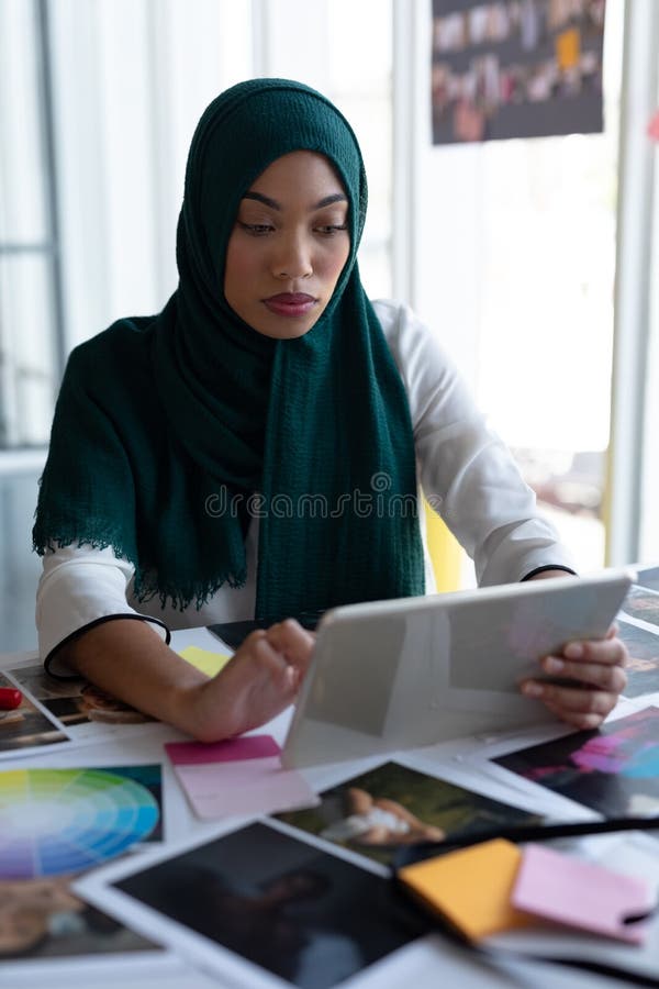 Żeński projektant grafik komputerowych w hijab używać cyfrową pastylkę przy biurkiem obraz royalty free Żeński projektant grafik komputerowych w hijab używać cyfrową pastylkę przy biurkiem obraz royalty free