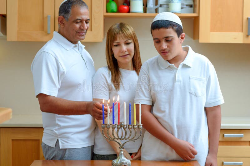 Żydowski tata, mama i nastolatek zapalają świece Chanukka w menorah na wakacje zdjęcie stock Żydowski tata, mama i nastolatek zapalają świece Chanukka w menorah na wakacje zdjęcie stock
