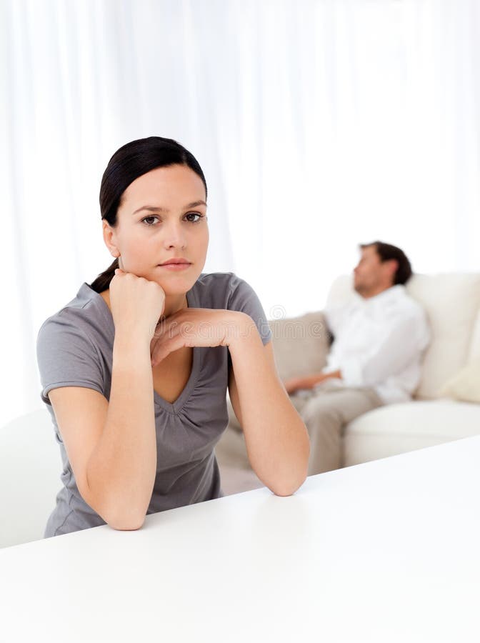 Worried woman in the living room while her boyfriend sleeping on the sofa. Worried woman in the living room while her boyfriend sleeping on the sofa