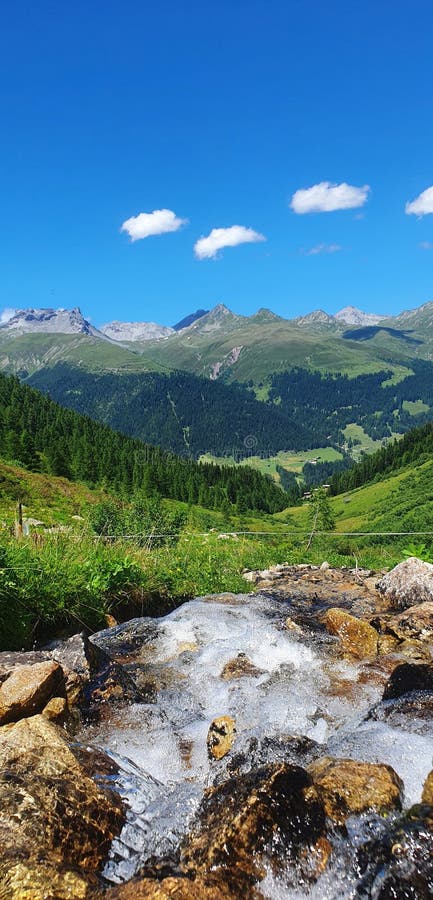 żywy krajobraz alpejski z jasnym strumieniem i niebieskim niebem zdjęcia stock