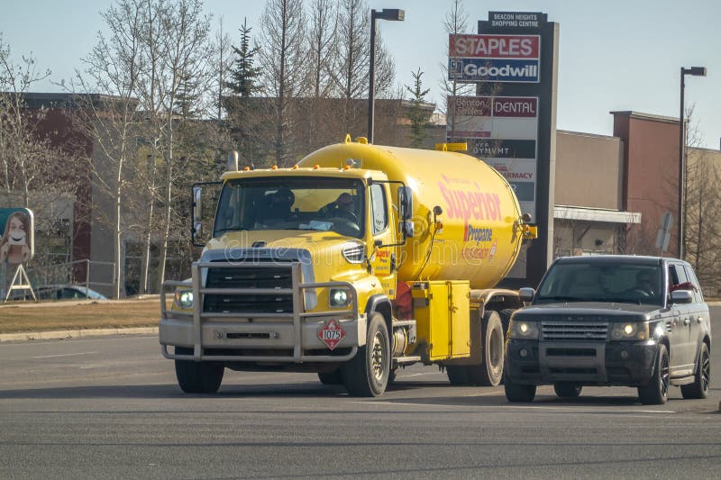Żółta ciężarówka Superior Propane jeździ po drodze obok czarnego SUV. Centrum handlowe zdjęcie stock