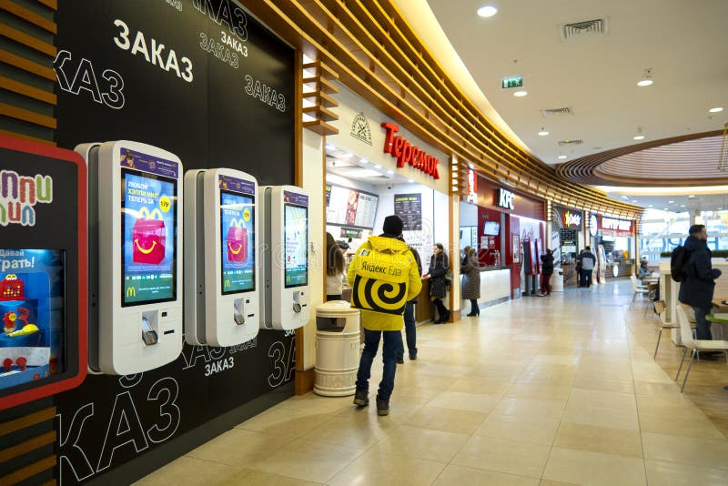 żółty plecak firmy świadczącej usługi dostawy 'Yandex Food' w restauracjach fast food wewnątrz centrum handlowego EUROPOLIS zdjęcia stock