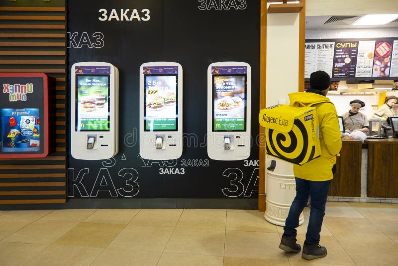 żółty plecak firmy świadczącej usługi dostawy 'Yandex Food' w restauracjach fast food wewnątrz centrum handlowego EUROPOLIS obrazy stock