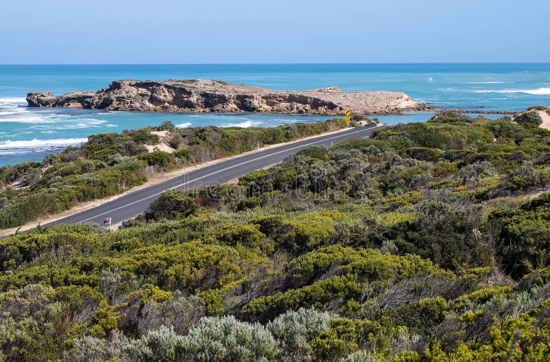 Șoseaua de coastă curbează apele turcoaz și stâncile stâncoase din Australia de Sud cu un indicator de avertizare rutieră royalty free stock photo