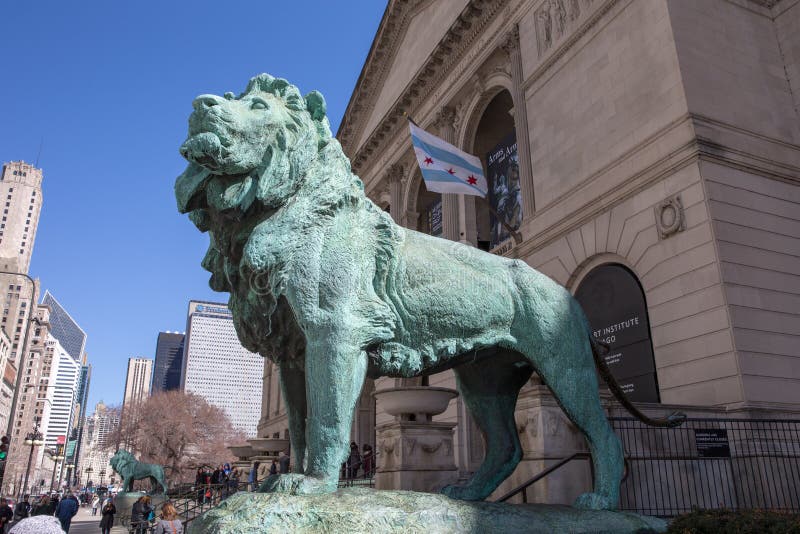 Chicago, USA - April 7, 2018: Bronze lion statue standing guard at the Art Institute of Chicago. There are two lion statues at the museum's Michigan Avenue entrance. They are famous Chicago landmarks and date to 1894. Chicago, USA - April 7, 2018: Bronze lion statue standing guard at the Art Institute of Chicago. There are two lion statues at the museum's Michigan Avenue entrance. They are famous Chicago landmarks and date to 1894.