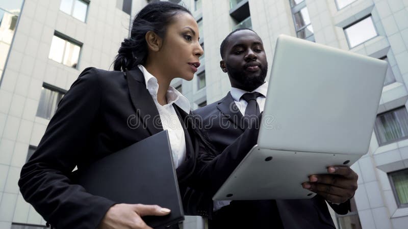 Άνδρας και γυναίκα που εξετάζουν το lap-top έξω από το κτήριο, πληρεξούσιοι, ολοκαίνουργια στοιχεία στοκ φωτογραφία με δικαίωμα ελεύθερης χρήσης Άνδρας και γυναίκα που εξετάζουν το lap-top έξω από το κτήριο, πληρεξούσιοι, ολοκαίνουργια στοιχεία στοκ φωτογραφία με δικαίωμα ελεύθερης χρήσης