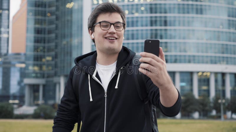 άνδρας που κάνει βιντεοκλήση χρησιμοποιώντας ακουστικά που περπατούν στο παρασκήνιο του κέντρου επιχειρήσεων