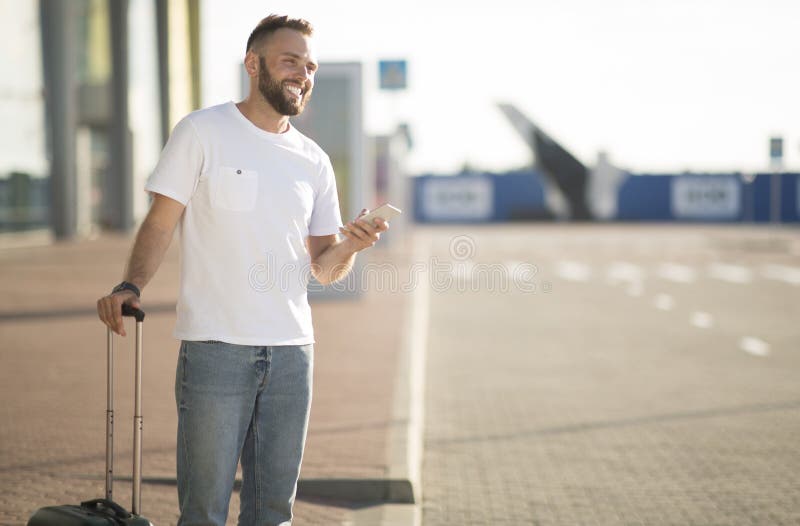 Man using phone app for ordering taxi, arriving at airport and waiting cab, free space. Man using phone app for ordering taxi, arriving at airport and waiting cab, free space