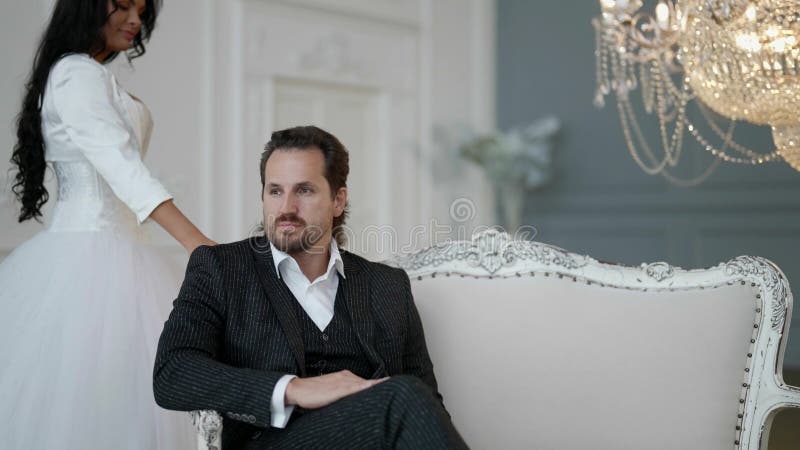 άνδρας τη μέρα του γάμου και η όμορφη νύφη του στο πολυτελές διαμέρισμα ετοιμάζονται για την τελετή στοκ φωτογραφία με δικαίωμα ελεύθερης χρήσης