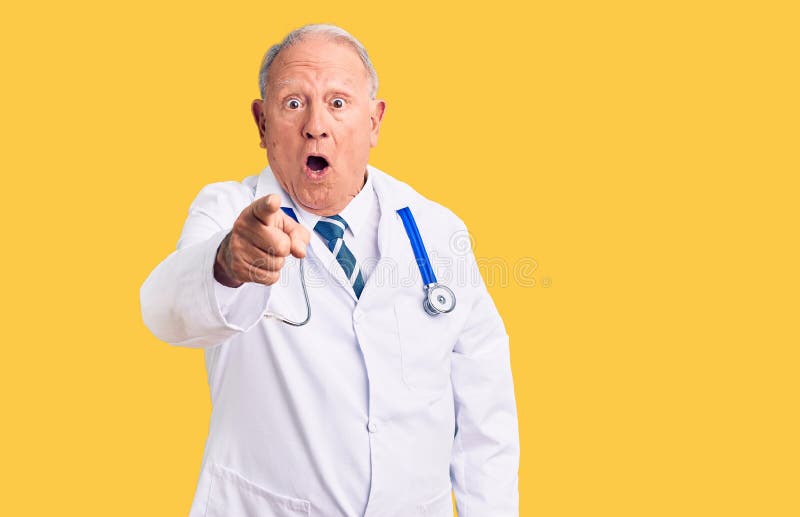 Senior handsome grey-haired man wearing doctor coat and stethoscope pointing displeased and frustrated to the camera, angry and furious with you. Senior handsome grey-haired man wearing doctor coat and stethoscope pointing displeased and frustrated to the camera, angry and furious with you