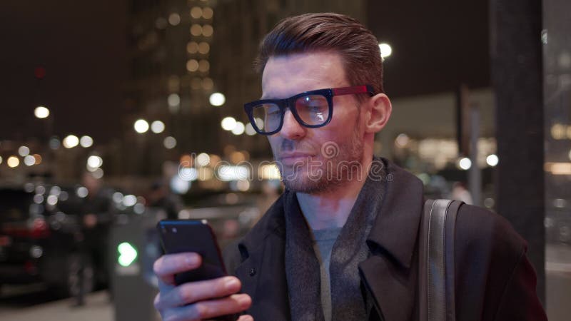 άντρας με γυαλιά με τηλέφωνο στο παρασκήνιο του εργοταξίου τη νύχτα