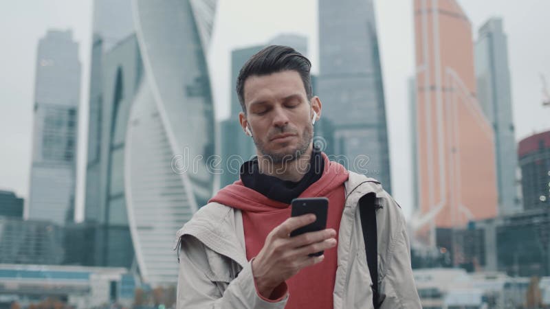 άντρας με κόκκινη κουκούλα που χτυπάει το τηλέφωνο στο φόντο ουρανοξύστες