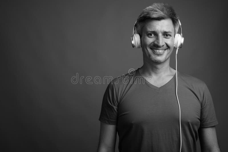 Άντρας με ξανθά μαλλιά που ακούει μουσική σε γκρίζο φόντο στοκ φωτογραφίες με δικαίωμα ελεύθερης χρήσης