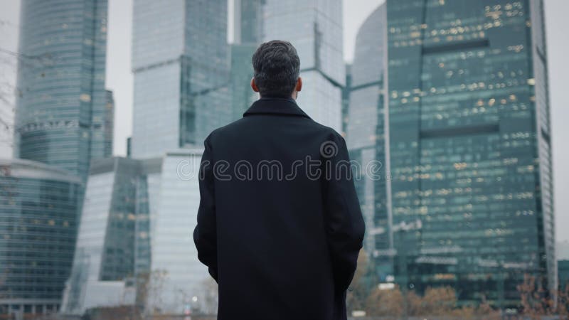 άντρας με παλτό περπατάει προς τα κτίρια επιχειρήσεων ουρανοξύστης αργή κίνηση