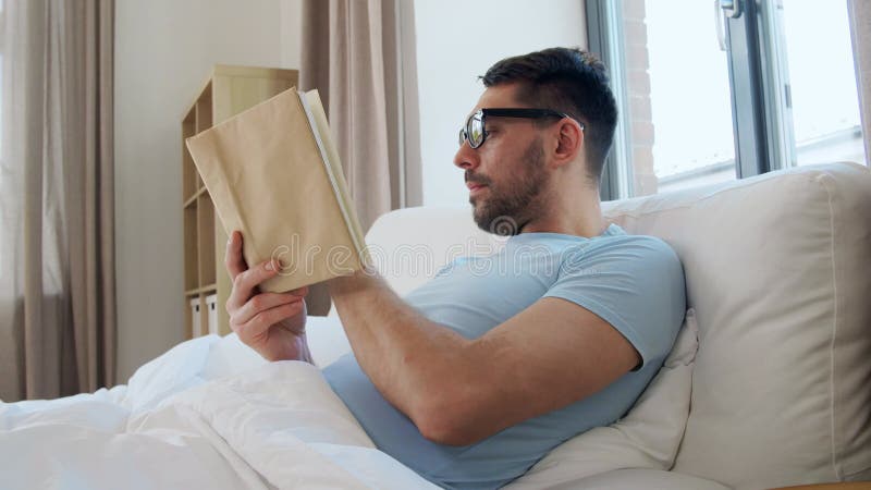 άντρας σε βιβλίο με γυαλιά στο κρεβάτι