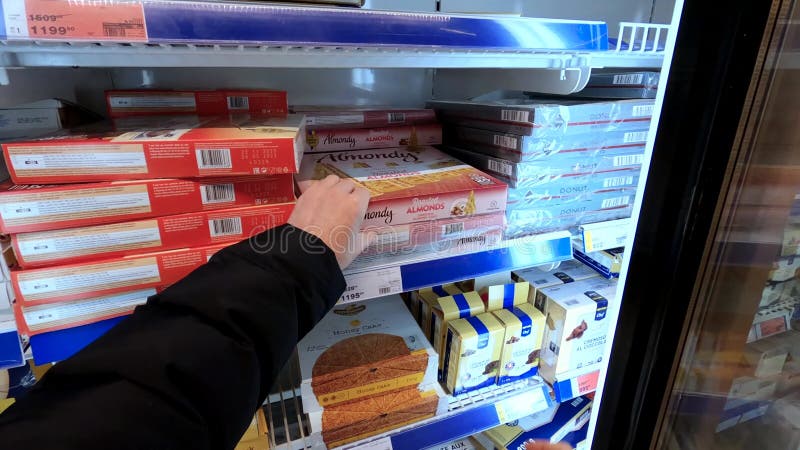 άποψη ενός αγοραστή που παίρνει ψητό κέικ αμυγδάλων από ψυγείο σε σούπερ μάρκετ.