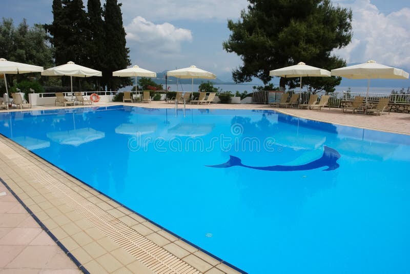 Άποψη της μπλε λίμνης και των λευκών ομπρελών στο ξενοδοχείο των σύγχρονων ελληνικών στοκ εικόνα με δικαίωμα ελεύθερης χρήσης Άποψη της μπλε λίμνης και των λευκών ομπρελών στο ξενοδοχείο των σύγχρονων ελληνικών στοκ εικόνα με δικαίωμα ελεύθερης χρήσης