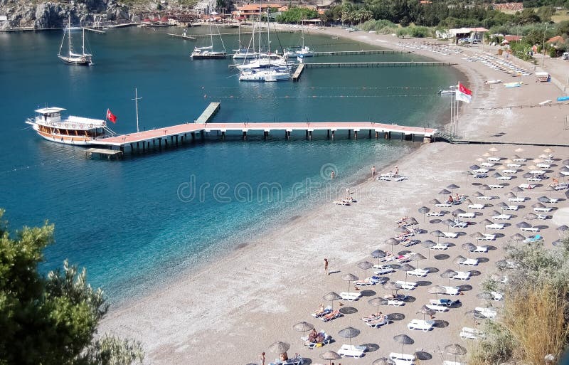 Άποψη της παραλίας, της μπλε λιμνοθάλασσας με το σαφές νερό και μιας αποβάθρας με στοκ φωτογραφίες Άποψη της παραλίας, της μπλε λιμνοθάλασσας με το σαφές νερό και μιας αποβάθρας με στοκ φωτογραφίες