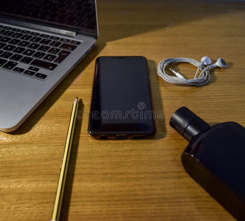 Άποψη του ξύλινου υπολογιστή γραφείου με το smartphone, το lap-top, τα ακουστικά, το μολύβι και το άρωμα στοκ φωτογραφίες Άποψη του ξύλινου υπολογιστή γραφείου με το smartphone, το lap-top, τα ακουστικά, το μολύβι και το άρωμα στοκ φωτογραφίες