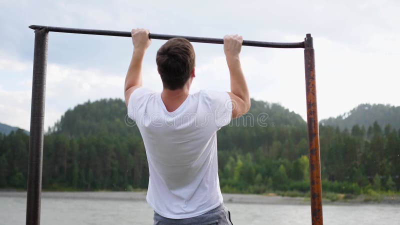 Άσκηση στον καθαρό αέρα Νεαρός δυνατός τύπος κάνει ασκήσεις στο μπαρ Φθινοπωρινό πάρκο