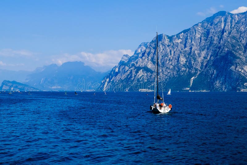 Άσπρο γιοτ σε μια μπλε λίμνη βουνών σε Malcesine, Ιταλία στοκ φωτογραφία με δικαίωμα ελεύθερης χρήσης Άσπρο γιοτ σε μια μπλε λίμνη βουνών σε Malcesine, Ιταλία στοκ φωτογραφία με δικαίωμα ελεύθερης χρήσης
