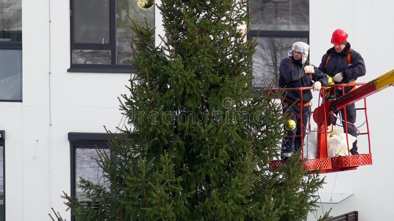 Άτομα που διακοσμούν το χριστουγεννιάτικο δέντρο στον υψηλό γερανό στην επίπεδη περιοχή σπιτιών