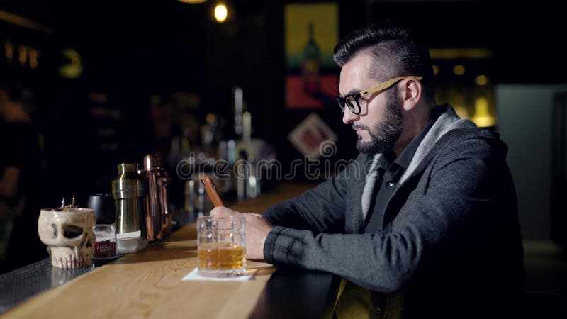 Άτομο που χρησιμοποιεί το smartphone κοντά στο ποτήρι του ποτού στο μετρητή φραγμών
