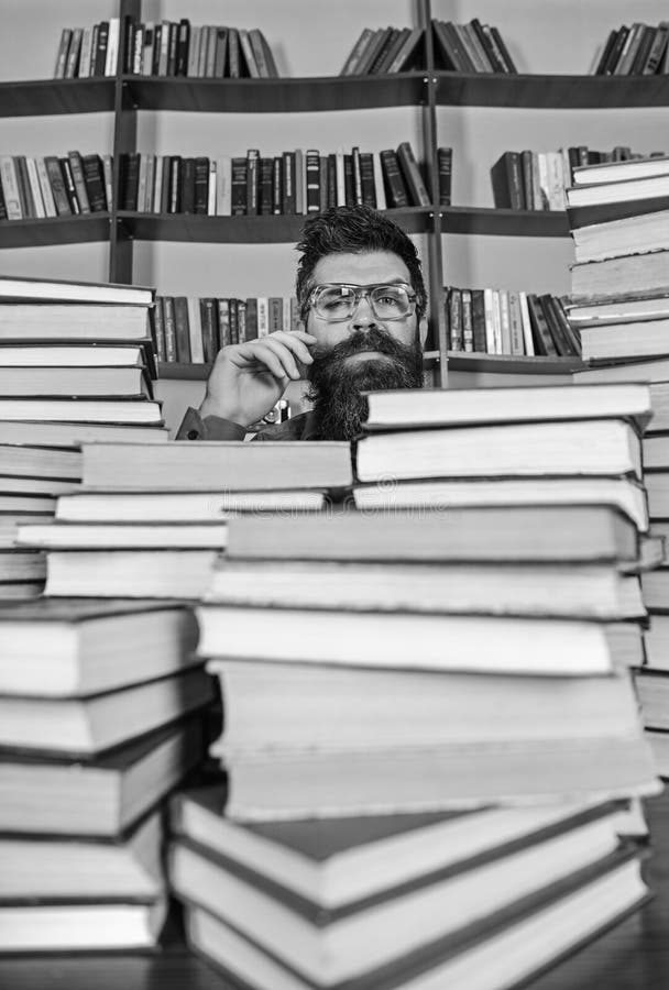 Άτομο στο στοχαστικό πρόσωπο μεταξύ των σωρών των βιβλίων στη βιβλιοθήκη, ράφια στο υπόβαθρο Ο δάσκαλος ή ο σπουδαστής με τη γενε στοκ εικόνες Άτομο στο στοχαστικό πρόσωπο μεταξύ των σωρών των βιβλίων στη βιβλιοθήκη, ράφια στο υπόβαθρο Ο δάσκαλος ή ο σπουδαστής με τη γενε στοκ εικόνες
