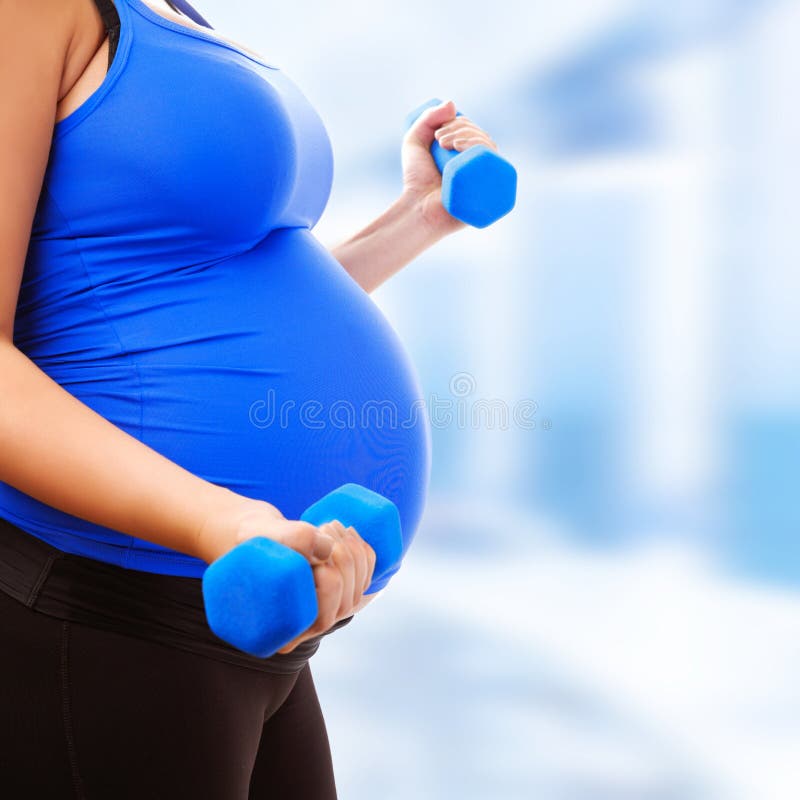 Pregnant female do exercise in sports hall, side view, body part, lifting dumbbells, active and sportive pregnancy, healthy motherhood concept. Pregnant female do exercise in sports hall, side view, body part, lifting dumbbells, active and sportive pregnancy, healthy motherhood concept