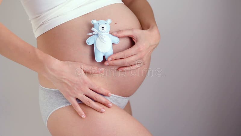 Έγκυο κορίτσι που κρατά λίγο μπλε χρώμα παιχνιδιών αρκούδων