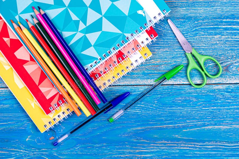 Colored pencils and notebooks with colored covers on a wooden table. September 1. Design. Background. High quality photo. Colored pencils and notebooks with colored covers on a wooden table. September 1. Design. Background. High quality photo