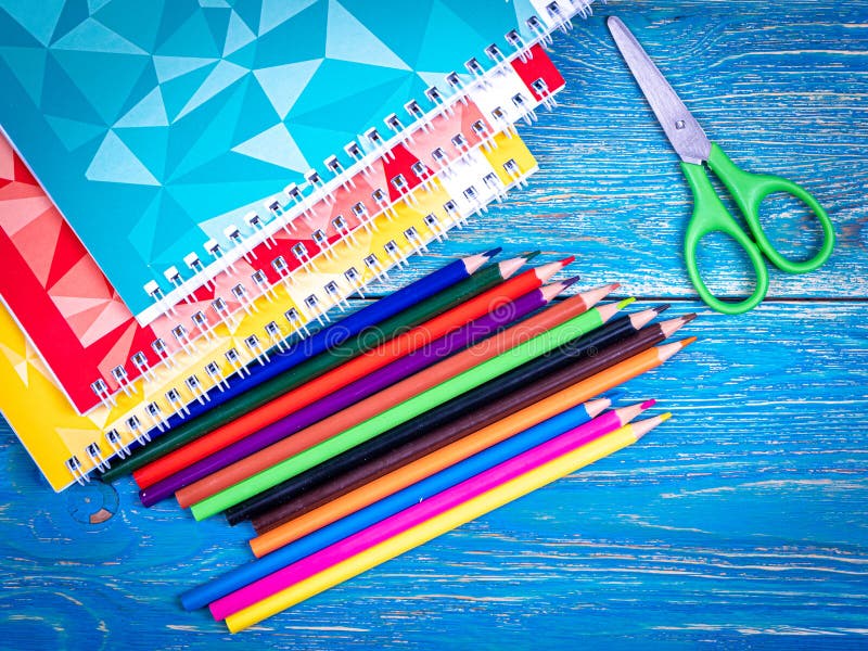 Colored pencils and notebooks on a wooden table with a vignette. September 1. Design. Background. High quality photo. Colored pencils and notebooks on a wooden table with a vignette. September 1. Design. Background. High quality photo