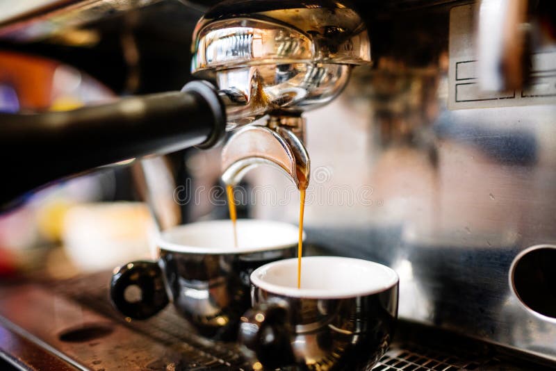 Close-up of espresso pouring from coffee machine into cups. Professional coffee brewing, barista details. Close-up of espresso pouring from coffee machine into cups. Professional coffee brewing, barista details
