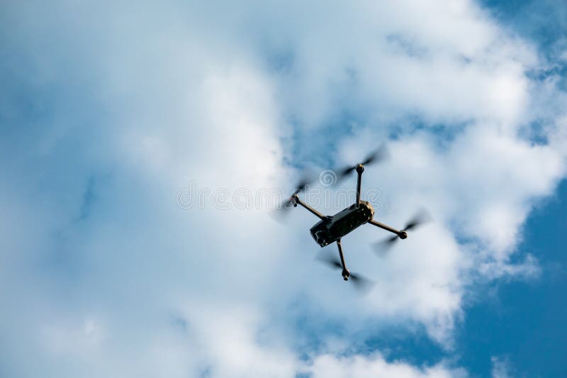 ένα drone dji που πετάει κάτω από λευκά σύννεφα και γαλάζιο ουρανό στοκ φωτογραφία